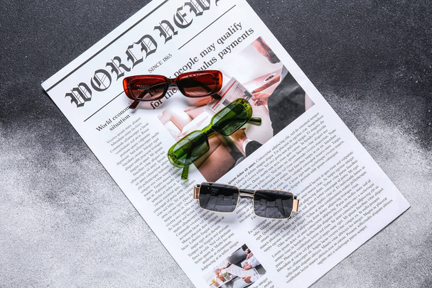 Κομψά γυαλιά ηλίου με εφημερίδα σε φόντο grunge - Φωτογραφία, εικόνα