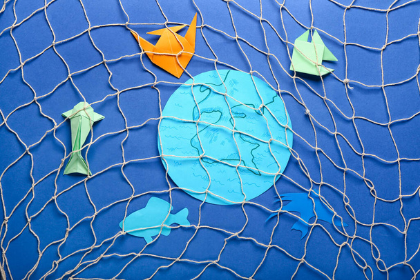紙の惑星地球と色の背景に網を持つ魚。生態学の概念 - 写真・画像