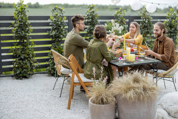 Young friends dining at backyard of the country house in nature - Foto, Imagen