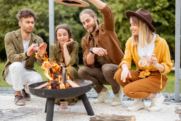 Group of young friends hang out by a fireplace at backyard - Photo, Image