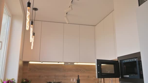 Brede hoek kantelfoto van moderne witte en houten beige keuken interieur - Video