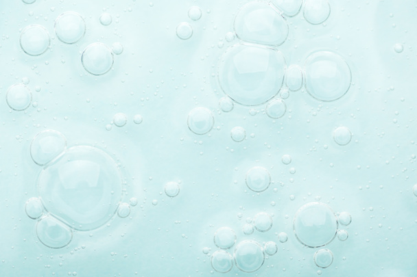 Gel detergente trasparente per la pelle del viso con bolle su fondo blu. La texture di un prodotto cosmetico di bellezza rinfresca e purifica la pelle. Gocce di siero spalmato. Prodotto naturale per la cura della pelle. - Foto, immagini