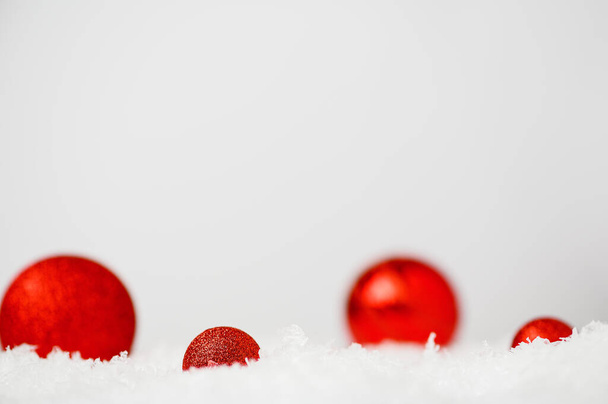 Beyaz yapay karda kırmızı Noel topları. Yılbaşı dekorlu hafif kış manzarası. Noel ağacı için şenlikli oyuncaklar. Boşluğu kopyala. - Fotoğraf, Görsel