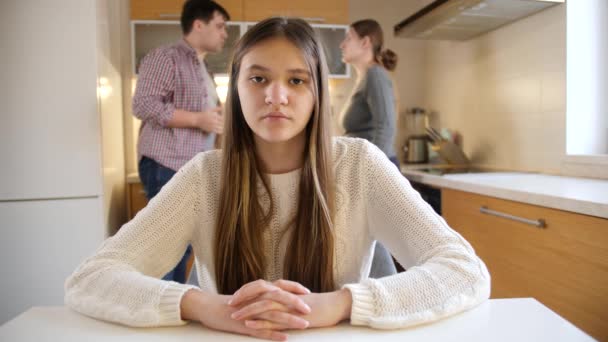 Nastolatka patrzy przed kamerą, podczas gdy rodzice kłócą się i mają konflikt w kuchni. Przemoc w rodzinie, konflikty i problemy w relacjach - Materiał filmowy, wideo