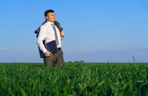 hombre de negocios trabaja en un campo verde, freelance y concepto de negocio, hierba verde y cielo azul como fondo - Foto, imagen