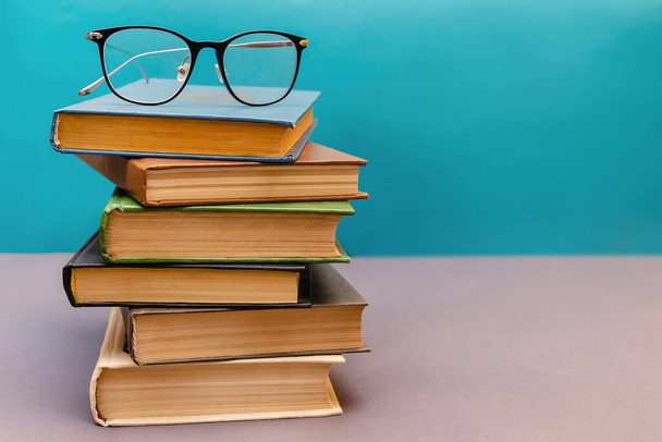 Stack of books with reading glasses on top - 写真・画像