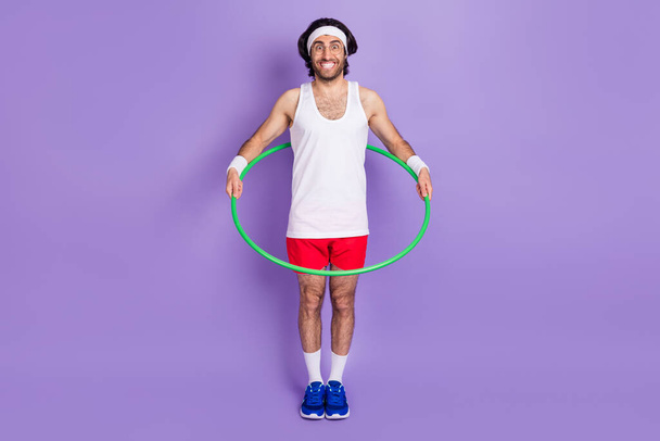 Full size photo of young crazy funky funny smiling man in glasses hold hula hoop isolated on purple color background - Foto, immagini