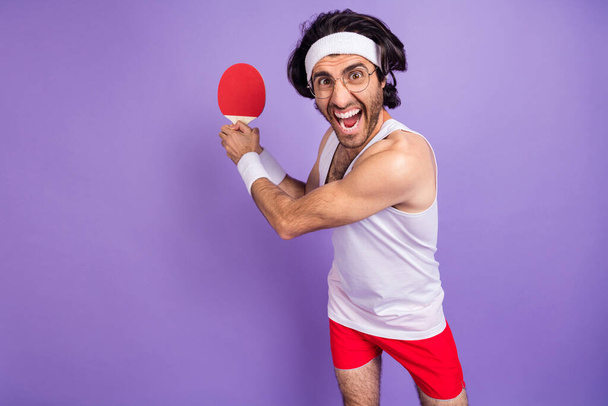 Fotografie mladého šťastného pozitivní blázen muž v brýlích křičí hrát stolní tenis izolované na fialové barvy pozadí - Fotografie, Obrázek