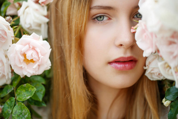 Beautiful young woman smells a rose flower - Photo, image