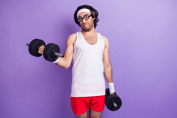 Photo of young funky funny serious man with hair and glasses hold dumbbells exercise isolated on purple color background - Zdjęcie, obraz