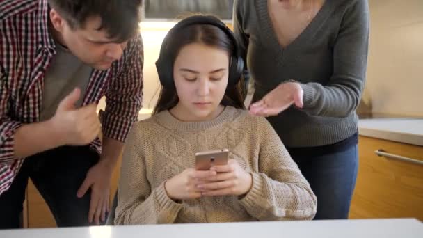 Genç kız müzik dinliyor ve akıllı telefon kullanıyor. Bu arada ebeveyn onunla tartışıyor ve bağırıyor. Aile içi şiddet, çatışmalar ve ilişki sorunları - Video, Çekim