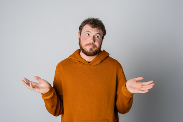 I dont know. Confused handsome bearded modern young man doubting and shrugging shoulders in questioning gesture, have no idea, standing against gray background - Foto, Imagem