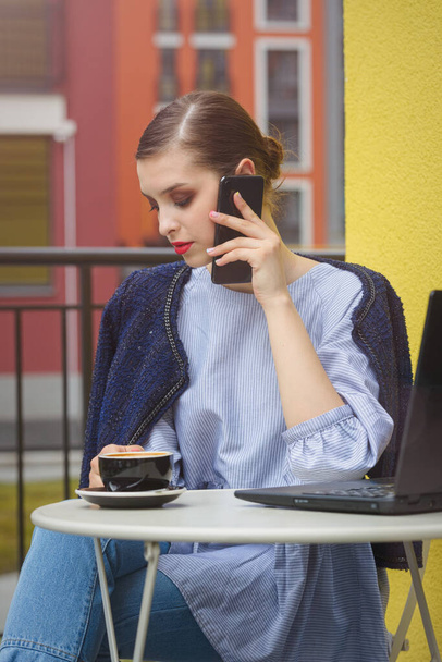 Uroczy szczęśliwy student kobieta komunikuje się przez telefon i korzystać z laptopa, aby przygotować się do pracy kursu. - Zdjęcie, obraz