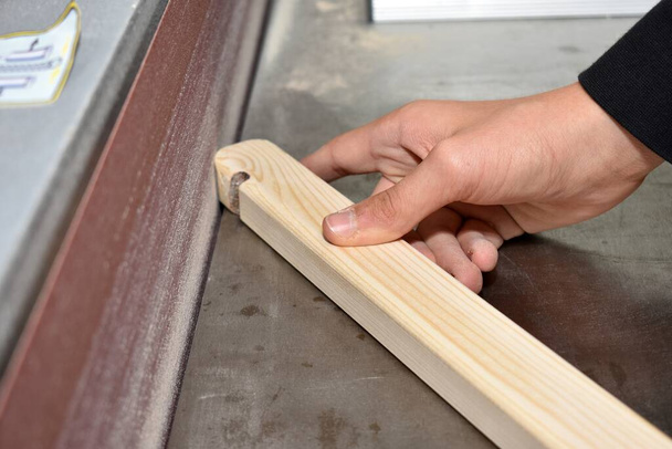 Craftsman grinds piece of wood on a belt sander - close-up carpenter - Photo, image