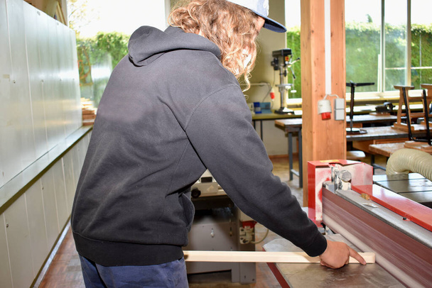 Carpenter grinds piece of wood on a belt grinder - craftsman carpenter - Valokuva, kuva