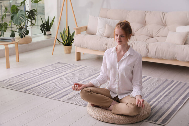 Woman meditating on wicker mat at home. Space for text - Foto, afbeelding