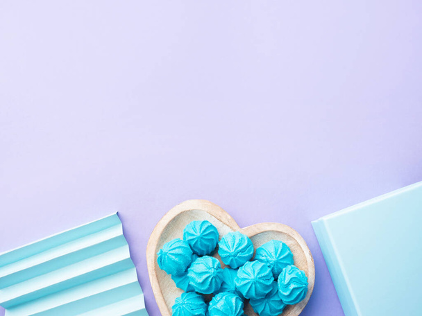 Merengue azul turquesa no prato em forma de coração com caixa de presente e decoração em fundo roxo pastel - Foto, Imagem