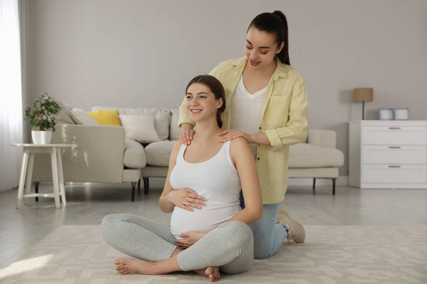 Doula massaging pregnant woman in living room. Preparation for child birth - Foto, Bild