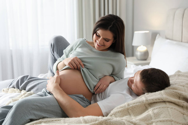 Young pregnant woman with her husband in bedroom - Foto, immagini
