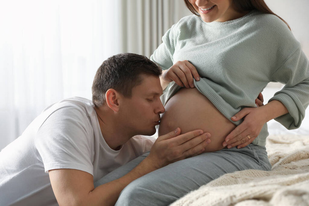 Young pregnant woman with her husband in bedroom, closeup - Fotó, kép