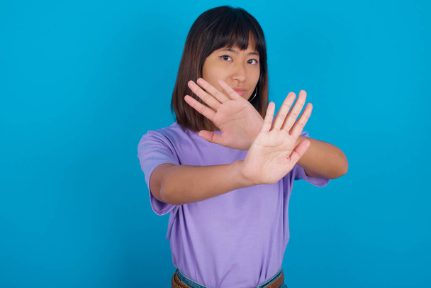 молода жінка має вираз відторгнення, що перетинає руки і долоні, роблячи негативний знак, розлючене обличчя
. - Фото, зображення