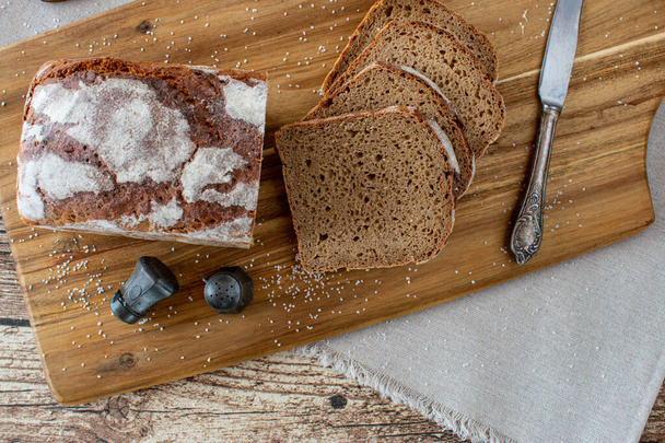 Rye Bread on wooden cutting board with salt and pepper shaker and rustic knife. Overhead and isolated view - Valokuva, kuva