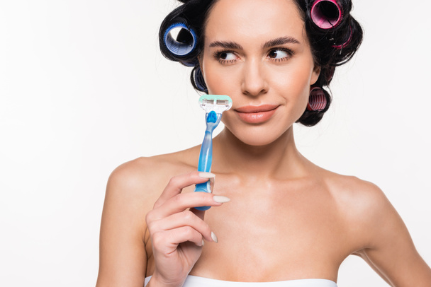 smiling young woman in curlers holding razor near face isolated on white - Photo, Image