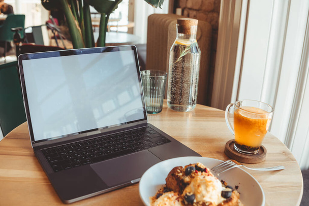 el portátil en la cafetería en la mesa con pantalla blanca en el espacio de copia de la cafetería - Foto, imagen