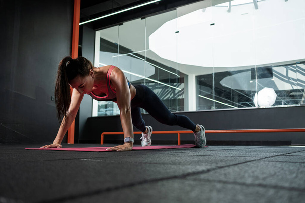 Athletic woman performing push-ups during training at gym - 写真・画像