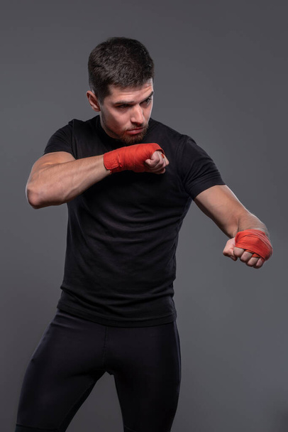 Sportsman with boxing bandages on hands working out defensive techniques - Фото, изображение