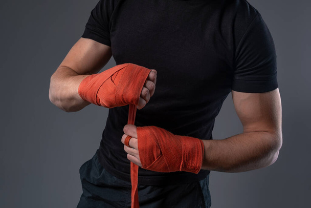Man wrapping hands with red tape, preparing for boxing - Foto, immagini