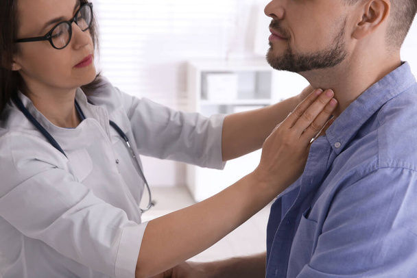 Doctor examining thyroid gland of patient in hospital, closeup - Фото, зображення