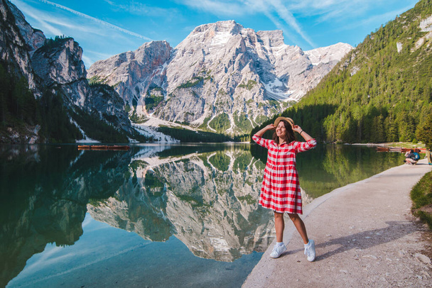 mujer en vestido rojo a cuadros con sombrero de paja mirando al lago de montaña. vacaciones de verano. concepto de viaje - Foto, Imagen