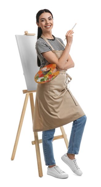 Young woman with drawing tools near easel on white background - Fotó, kép