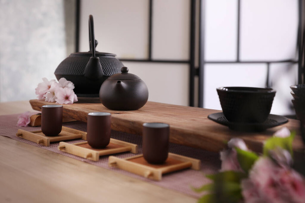 Beautiful set for traditional tea ceremony and sakura flowers on wooden table - 写真・画像