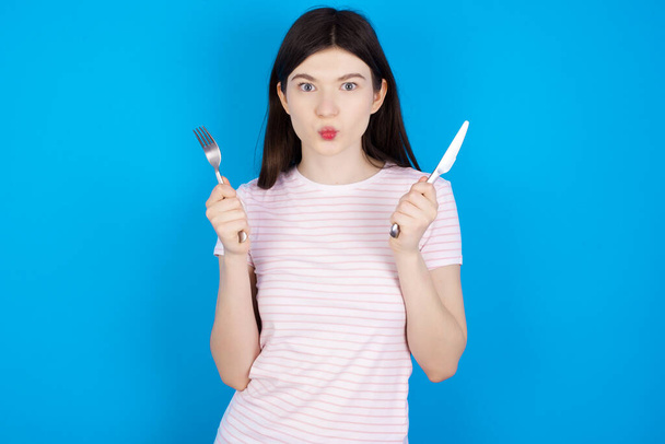 hungry young brunette woman holding in hand fork knife want tasty yummy pizza pie - Foto, afbeelding