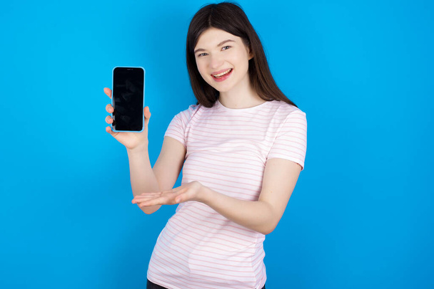 fiatal barna nő egy mobillal. okostelefon bemutatása. Reklámkoncepció. - Fotó, kép