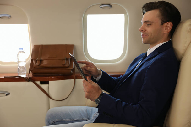Businessman working on tablet in airplane during flight - Foto, afbeelding