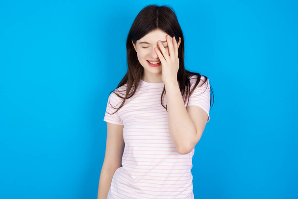 young brunette woman makes face palm and smiles broadly, giggles positively hears funny joke poses - Fotoğraf, Görsel