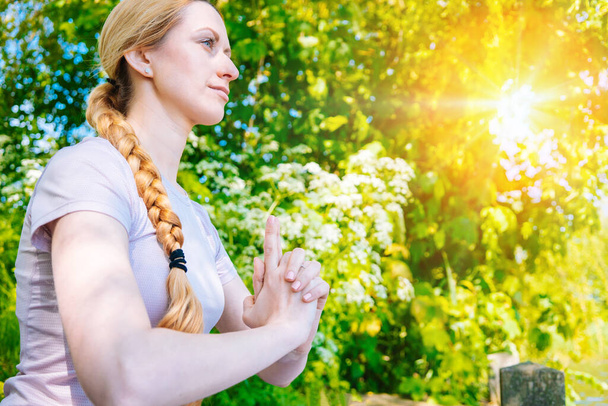 jovem mulher fazendo ioga asana no parque. exercício de alongamento menina na posição de ioga. mulher feliz e saudável sentada em posição de lótus e praticando ioga. meditação e esporte ao pôr do sol ao ar livre. - Foto, Imagem