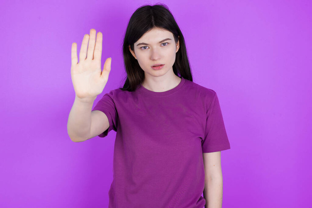 young brunette woman doing stop sing with palm of the hand. Warning expression with negative and serious gesture on the face. - Photo, Image