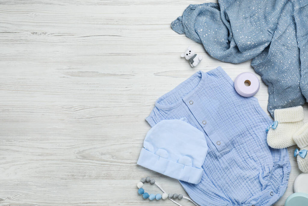 Flat lay composition with baby clothes and accessories on white wooden table. Space for text - Valokuva, kuva