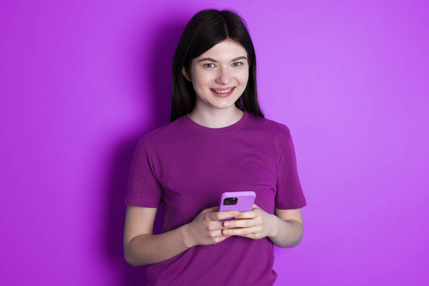 młoda brunetka kobieta cieszy się odległą komunikacją, używa telefonu komórkowego, surfuje szybko nieograniczony internet, ma przyjemny uśmiech, sprawia, że zakupy online - Zdjęcie, obraz