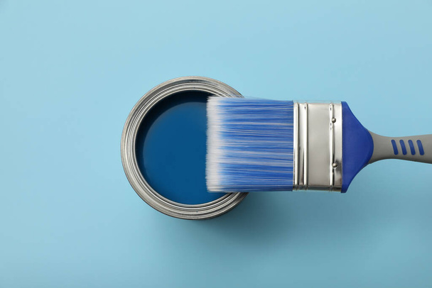 Can of paint and brush on light blue background, top view - Φωτογραφία, εικόνα
