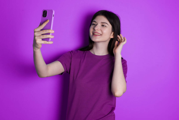nuori brunette nainen hymyilee ja ottaa selfie valmis lähettämään sen hänen sosiaalinen media. - Valokuva, kuva