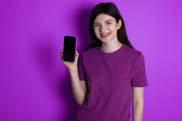 Smiling young brunette woman Mock up copy space. Hold mobile phone with blank empty screen - Фото, зображення