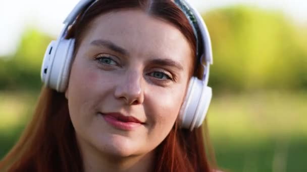 Kaukasische glückliche Frau mit Kopfhörern, die auf der Straße läuft und draußen Musik hört. - Filmmaterial, Video