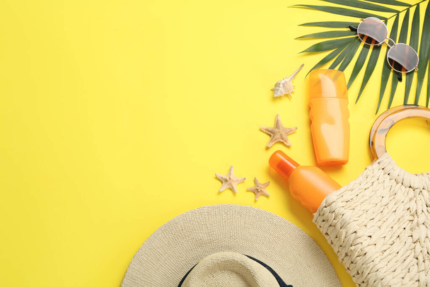 Sun protection products and beach accessories on yellow background, flat lay. Space for text - Zdjęcie, obraz
