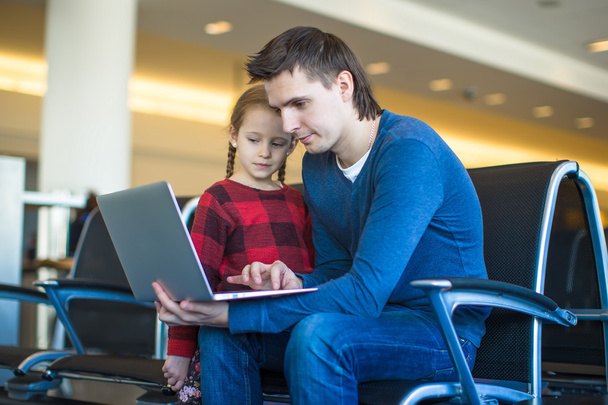 Padre y niña con portátil en el aeropuerto mientras espera su vuelo
 - Foto, imagen