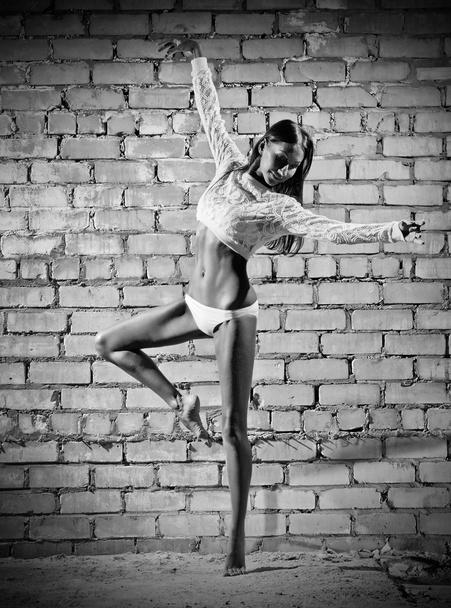 Young dancing woman on brick wall background (monochrome ver) - Zdjęcie, obraz
